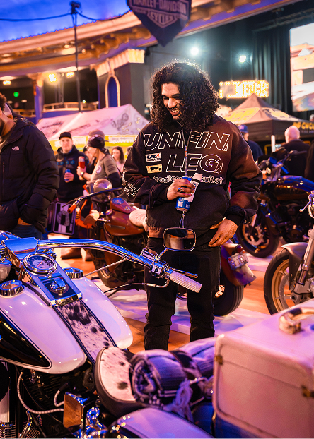 Attendee standing among rows of custom motorcycles displayed under bright event lighting