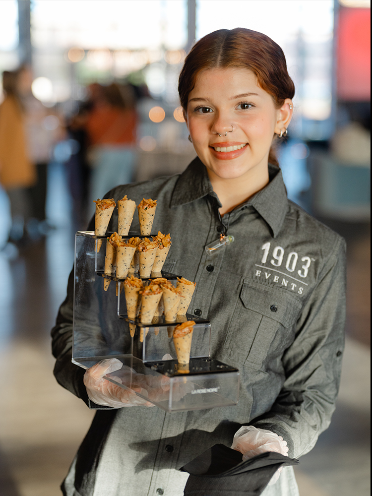 Server holding tray of bite-sized appetizers at indoor event
