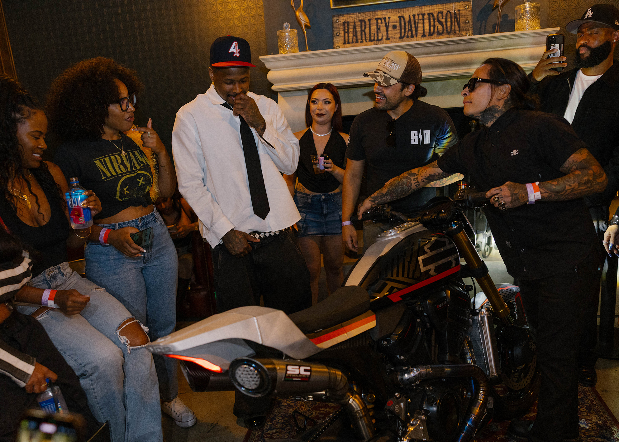 Rapper YG admires SMCO’s custom Harley-Davidson Pan America ST surrounded by people in the VIP section backstage at Bike Shed Moto Co.