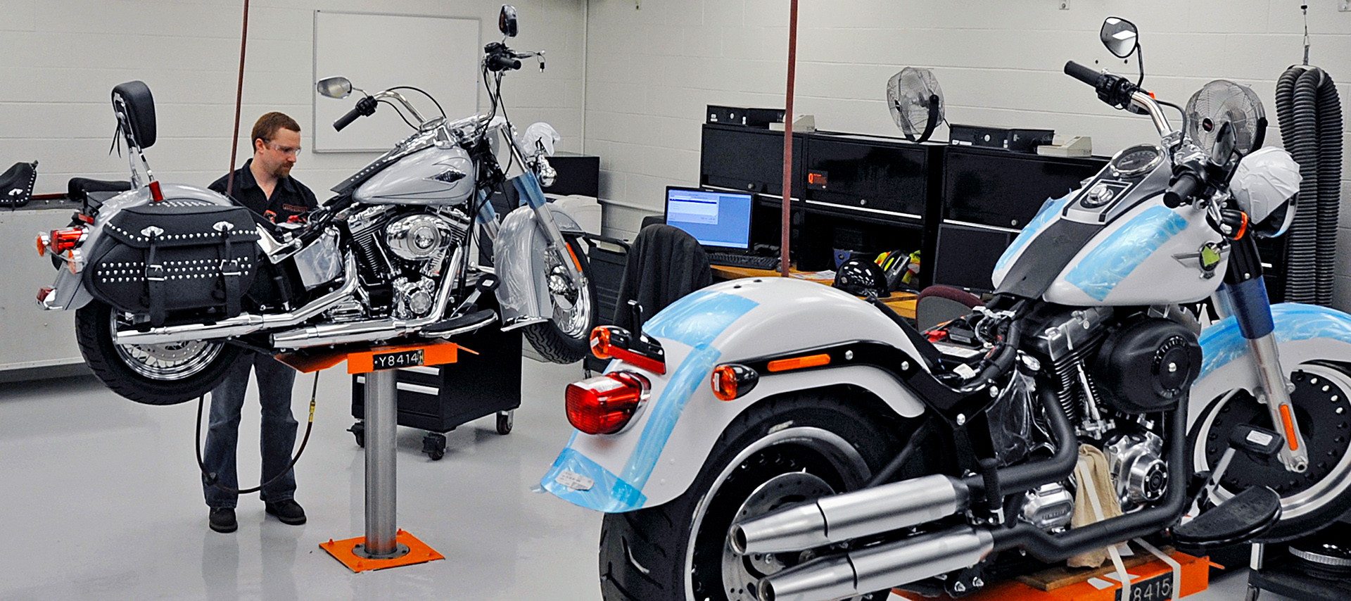 Two Harley-Davidson motorcycles on lifts in a service workshop
