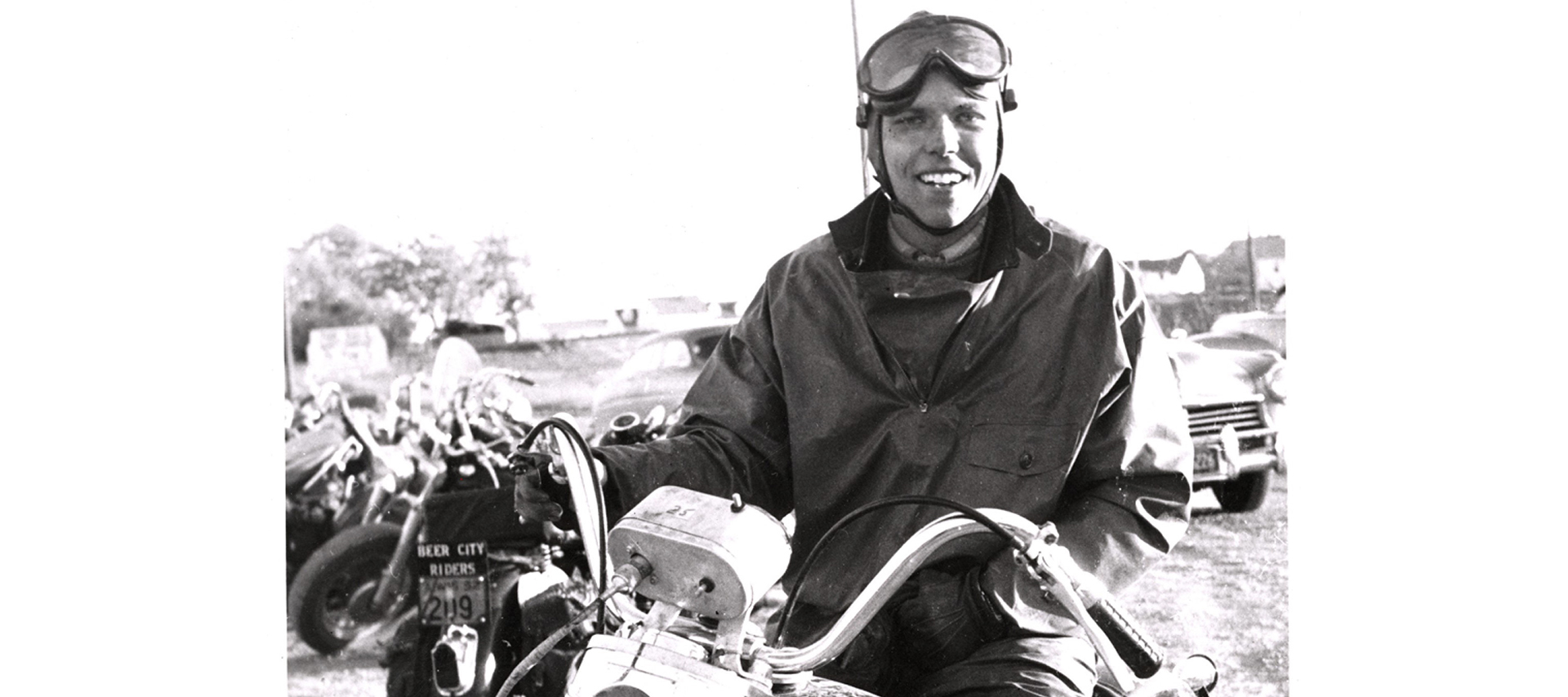 A man smiles while sitting on a motorcycle