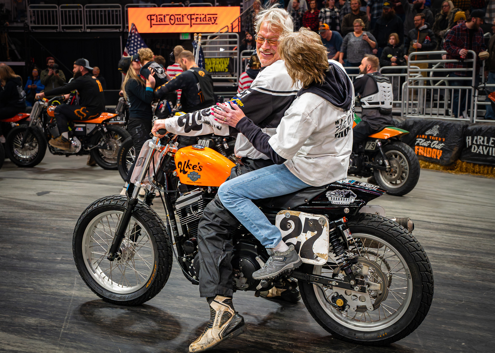 A man and a woman sit on a race bike together
