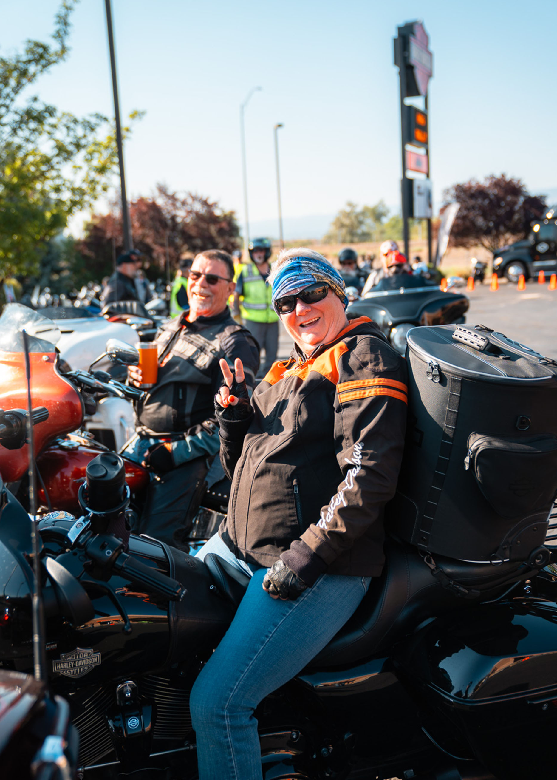A woman holds up a peace sign while sitting on her parked motorcycle