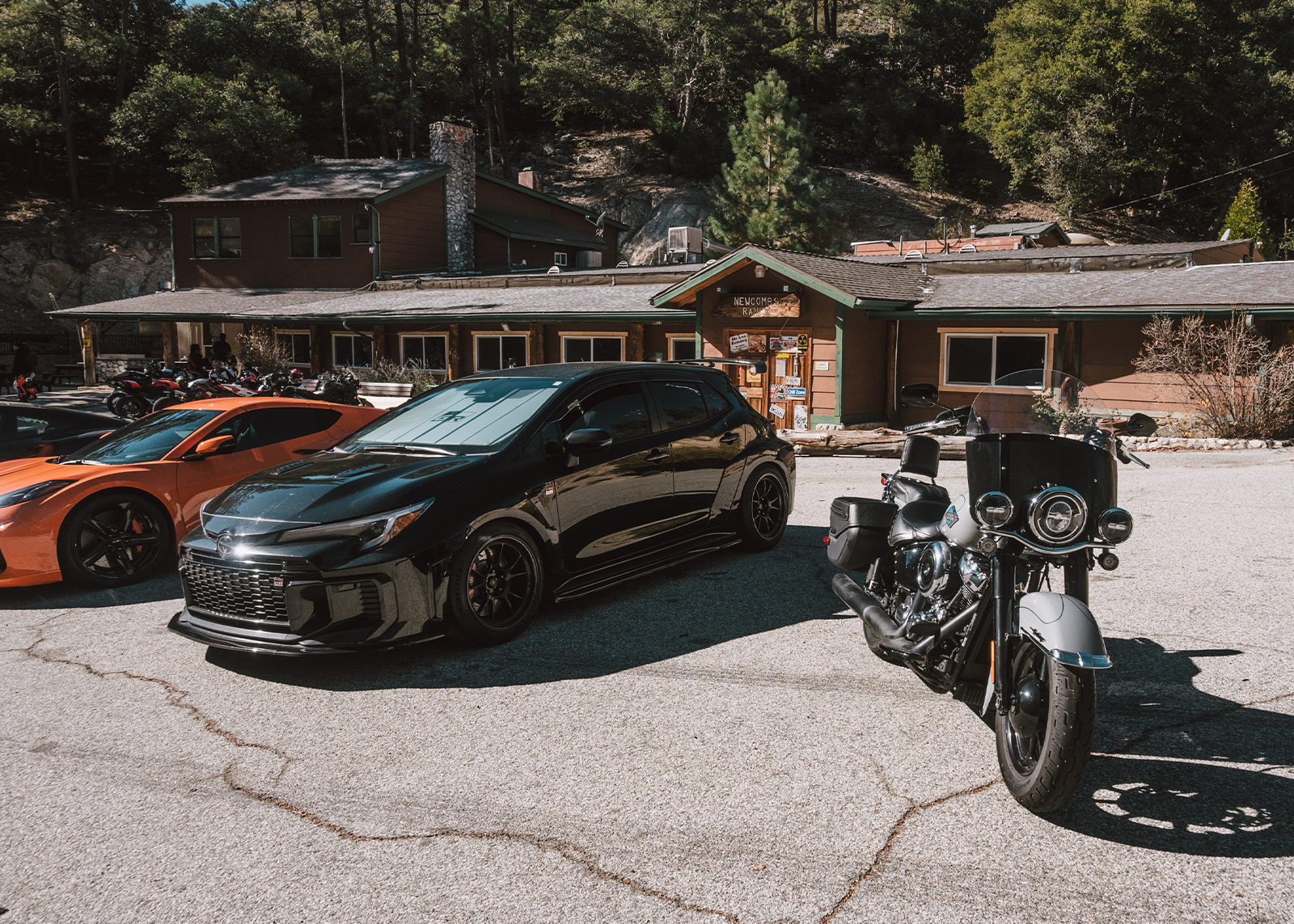A Harley-Davidson Heritage Classic motorcycle parked next to sports cars at Newcomb’s Ranch