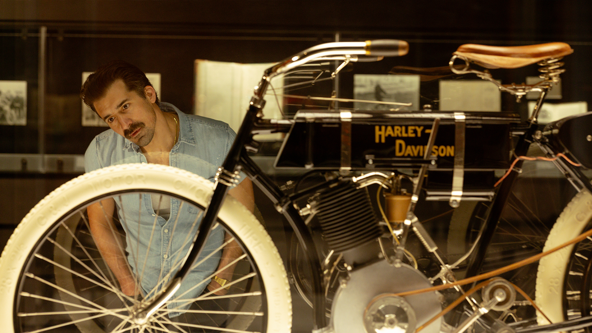 Visitor examining vintage motorcycle behind glass display