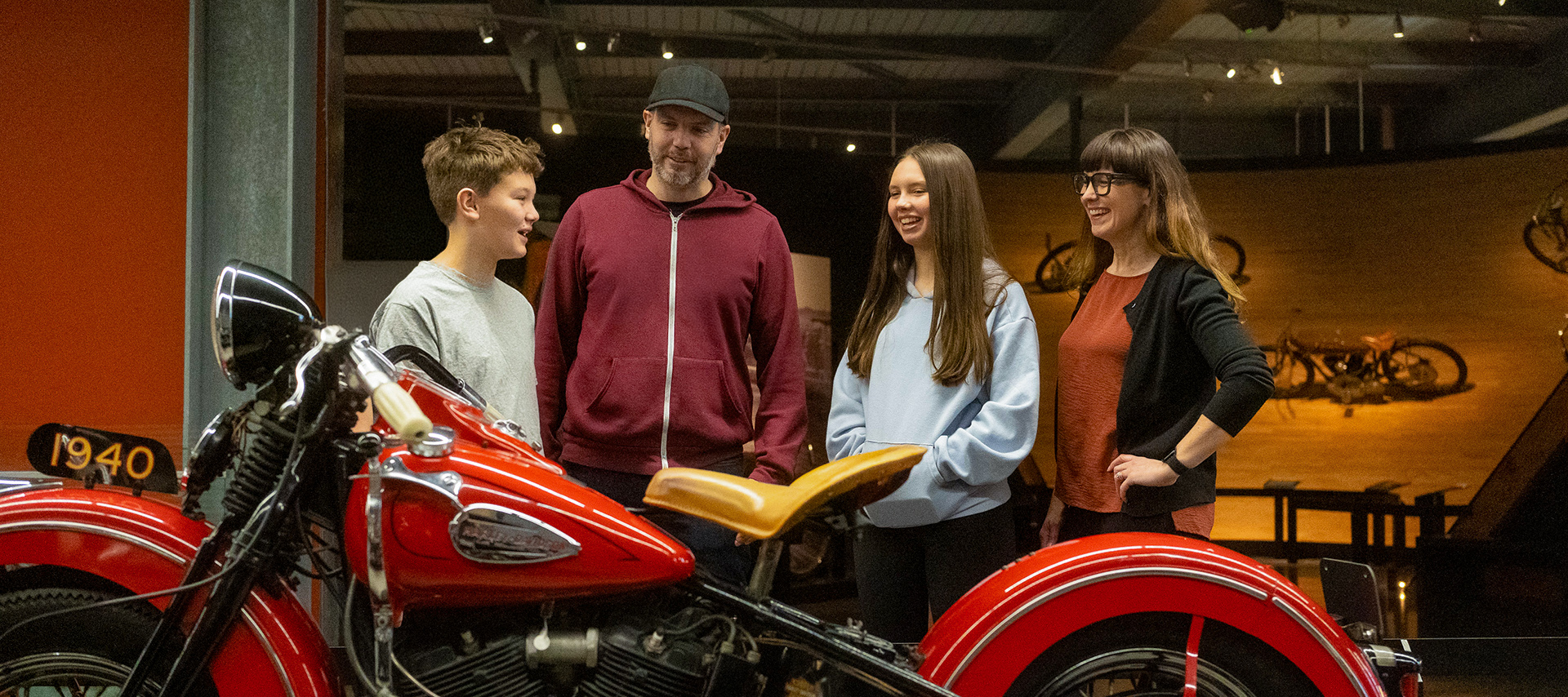Family viewing vintage red Harley-Davidson motorcycle in museum