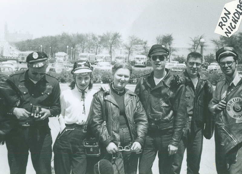 Archival group photo of motorcycle club members in riding caps and leather jackets at an outdoor gathering