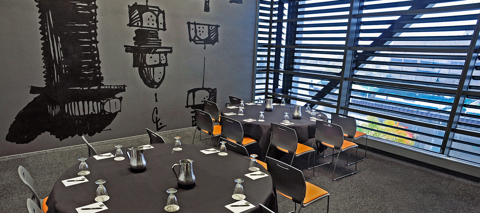 Round table setup with black linens and orange chairs in meeting room