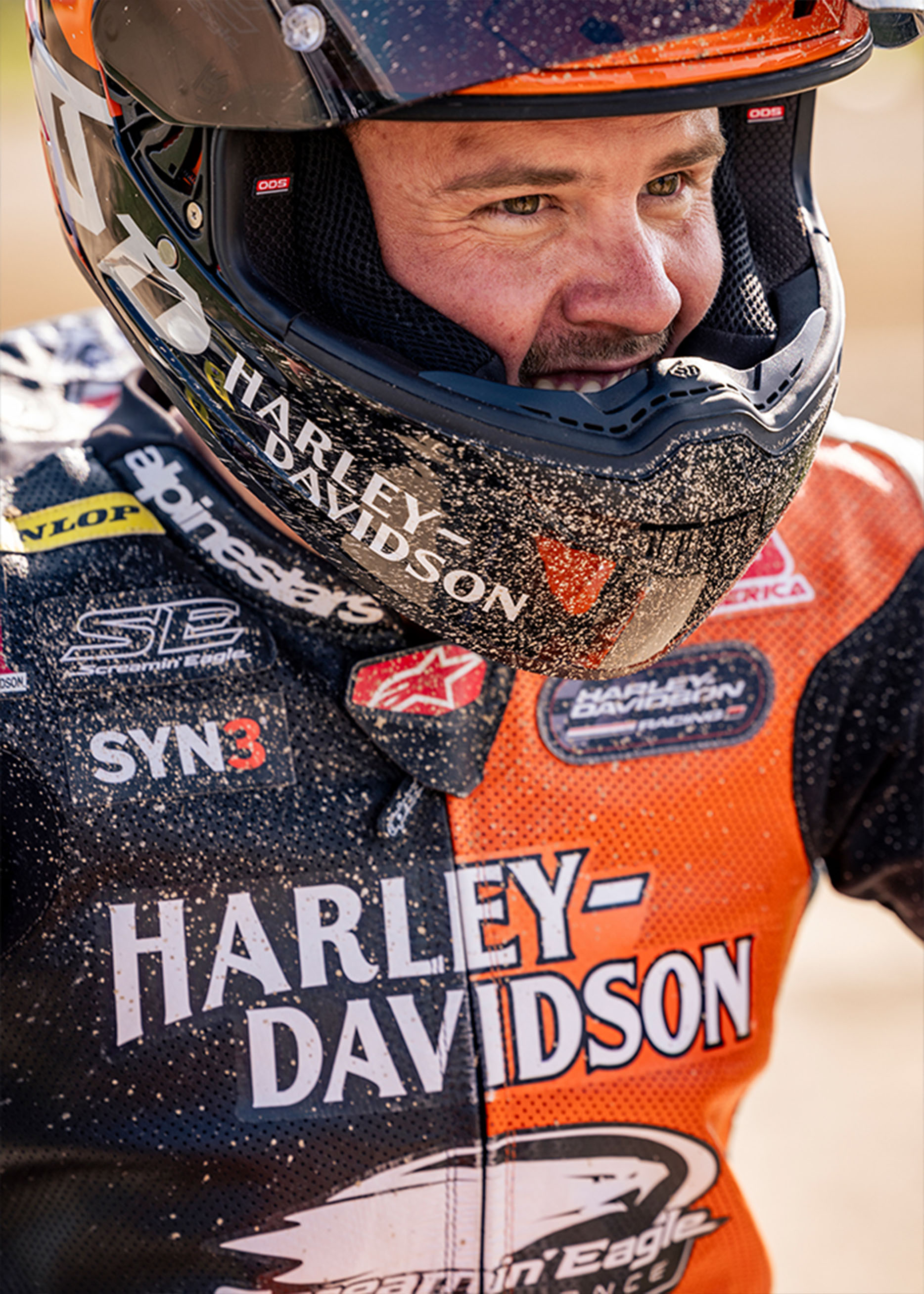 Kyle Wyman smiles in his dirt-covered helmet and leathers