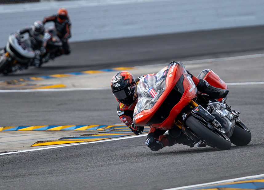 Kyle Wyman leans sharply through an S curve, with another rider approaching in the distant background