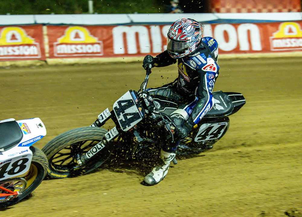 Rider aboard motorcycle No. 44 slides through a dirt-track corner under stadium lights