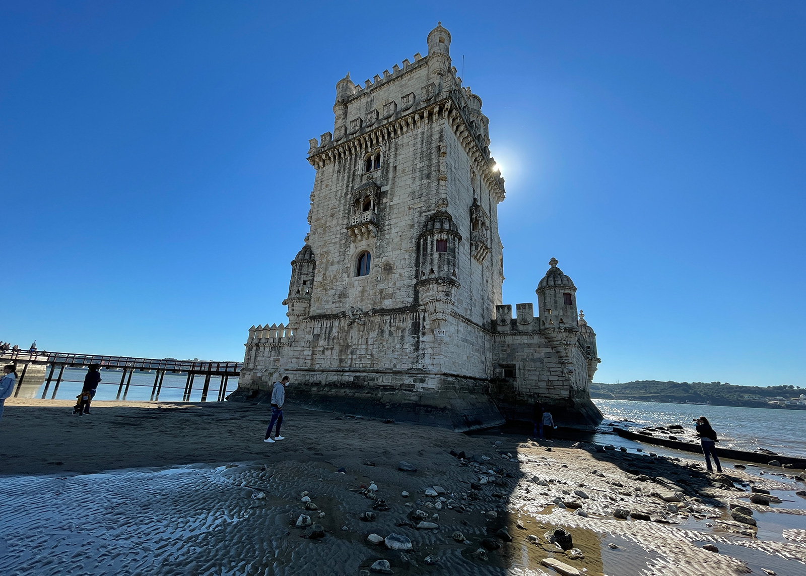 Historic stone tower rising from shoreline under clear blue sky in Lisbon