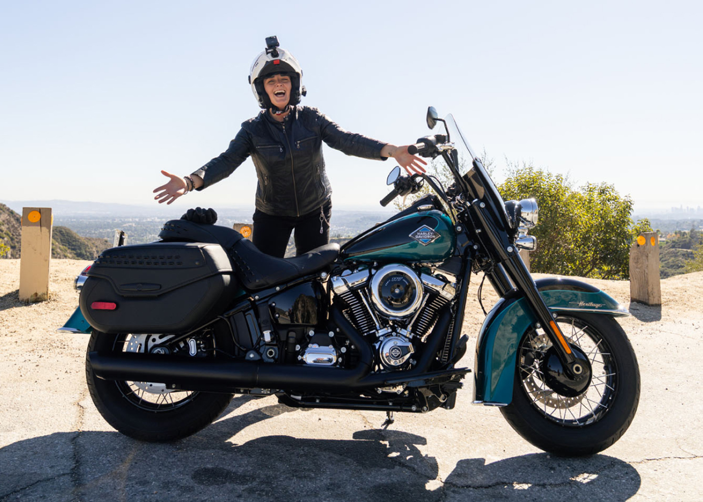Pessoa parada atrás de uma motocicleta HD azul-petróleo em um mirante cênico