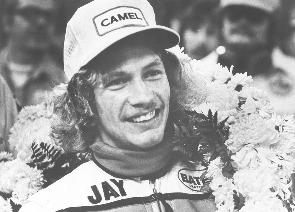 Black-and-white close-up of Jay Springsteen wearing a victory wreath after a race win