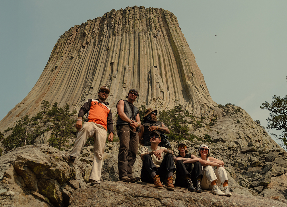 Travelers gather at the base of Devils Tower, framed by the monument’s towering rock columns