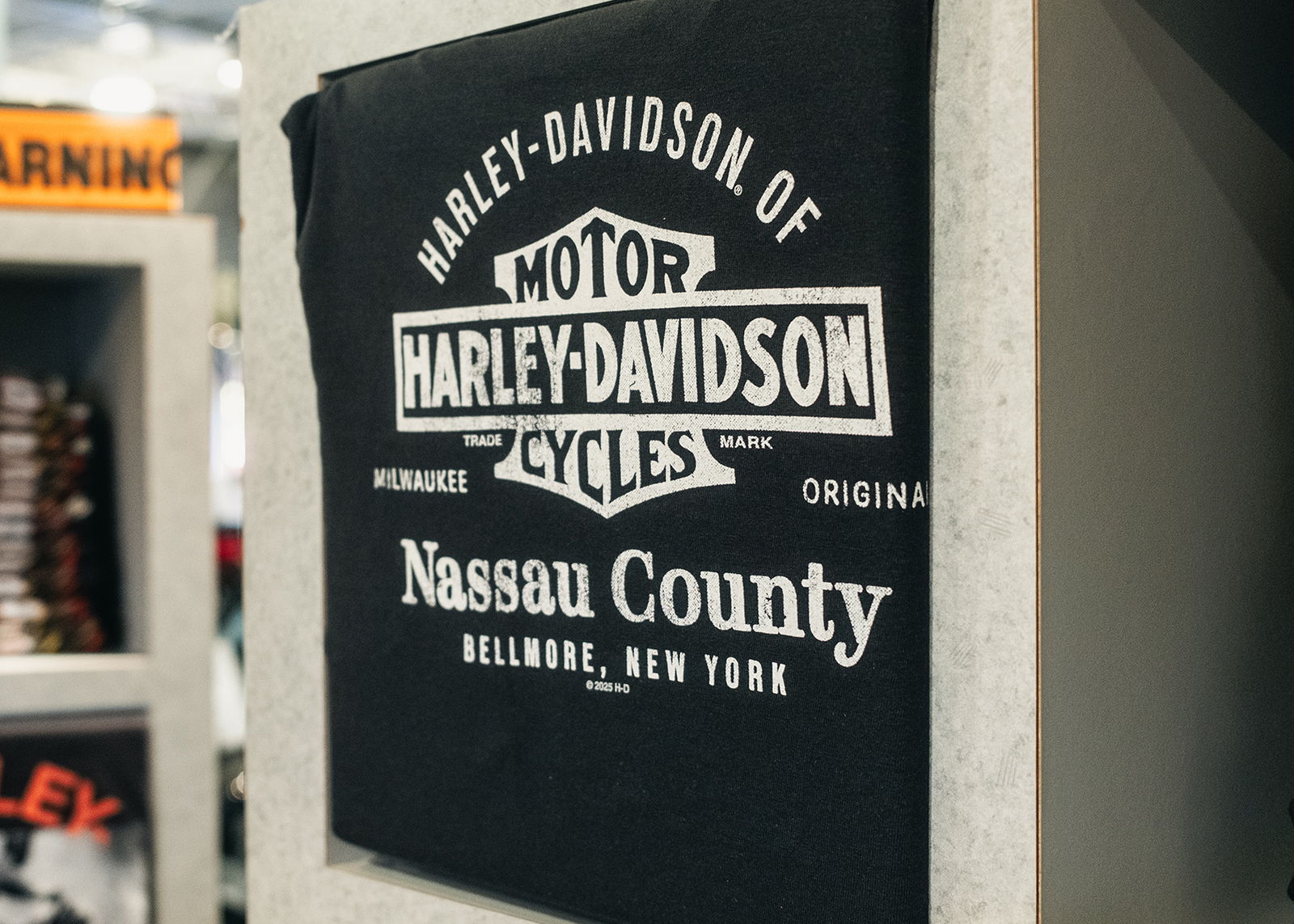 A display of a black t-shirt with a white Harley-Davidson of Nassau County design.