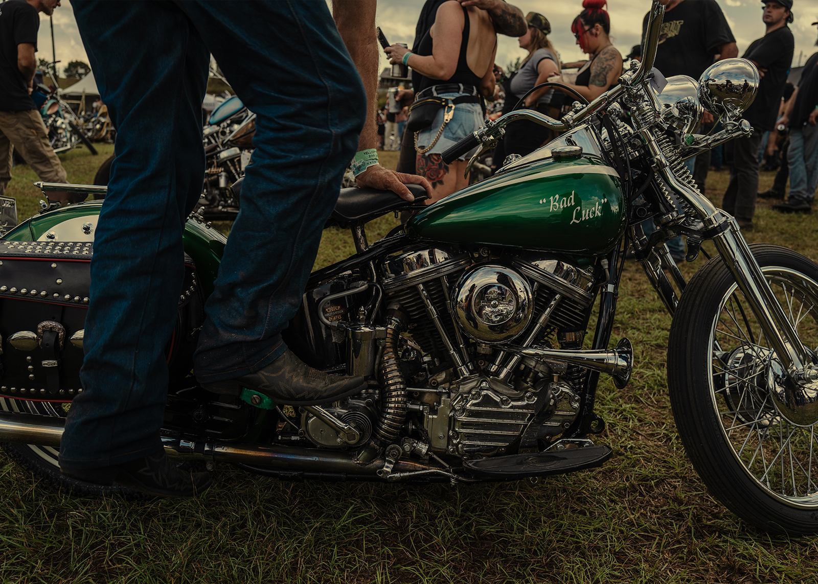 A rider kick-starts a green Harley-Davidson chopper named “Bad Luck” surrounded by people at the Born motorcycle Free Texas rally.
