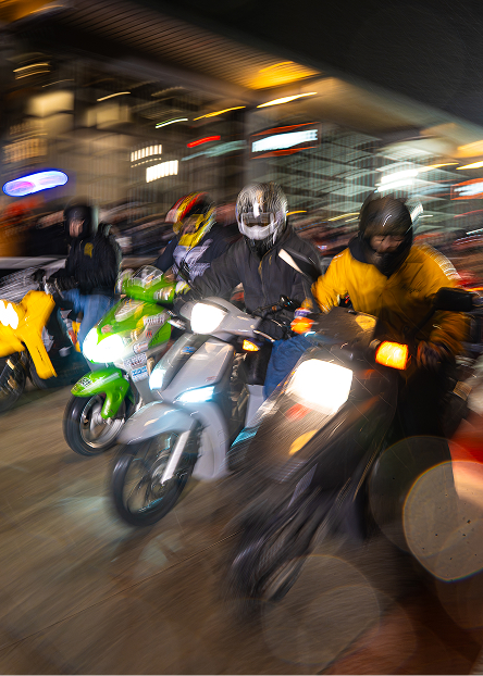 4 scooters race side by side outside the Harley-Davidson Museum with spectators lining the track