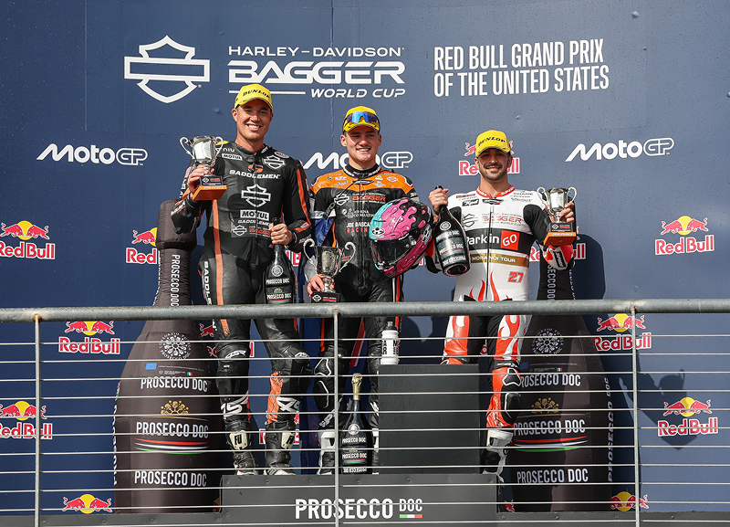 Podium ceremony with top three motorcycle racers holding trophies after the race event