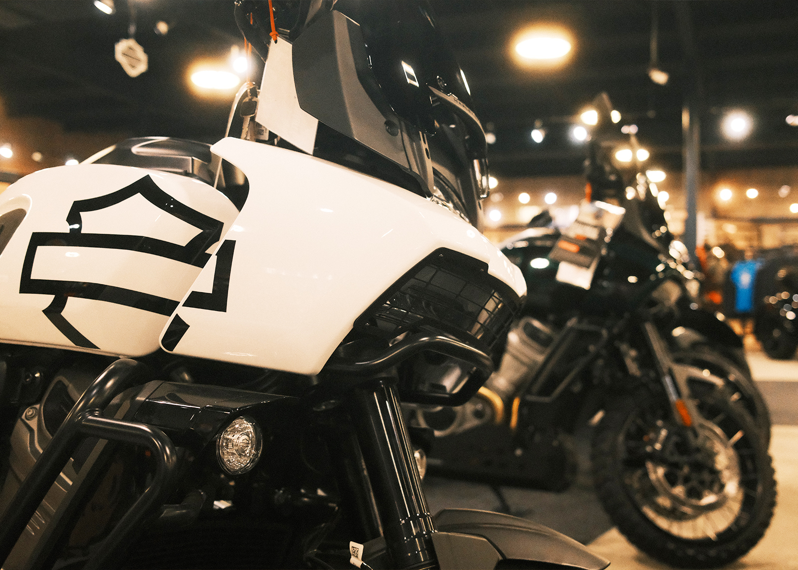 A close up of a white Harley-Davidson Pan America, with other motorcycles in the background.