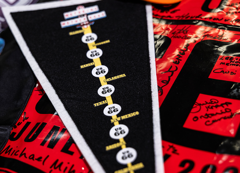 Vertical Route 66 pennant with stops in different cities marked along a route in the center