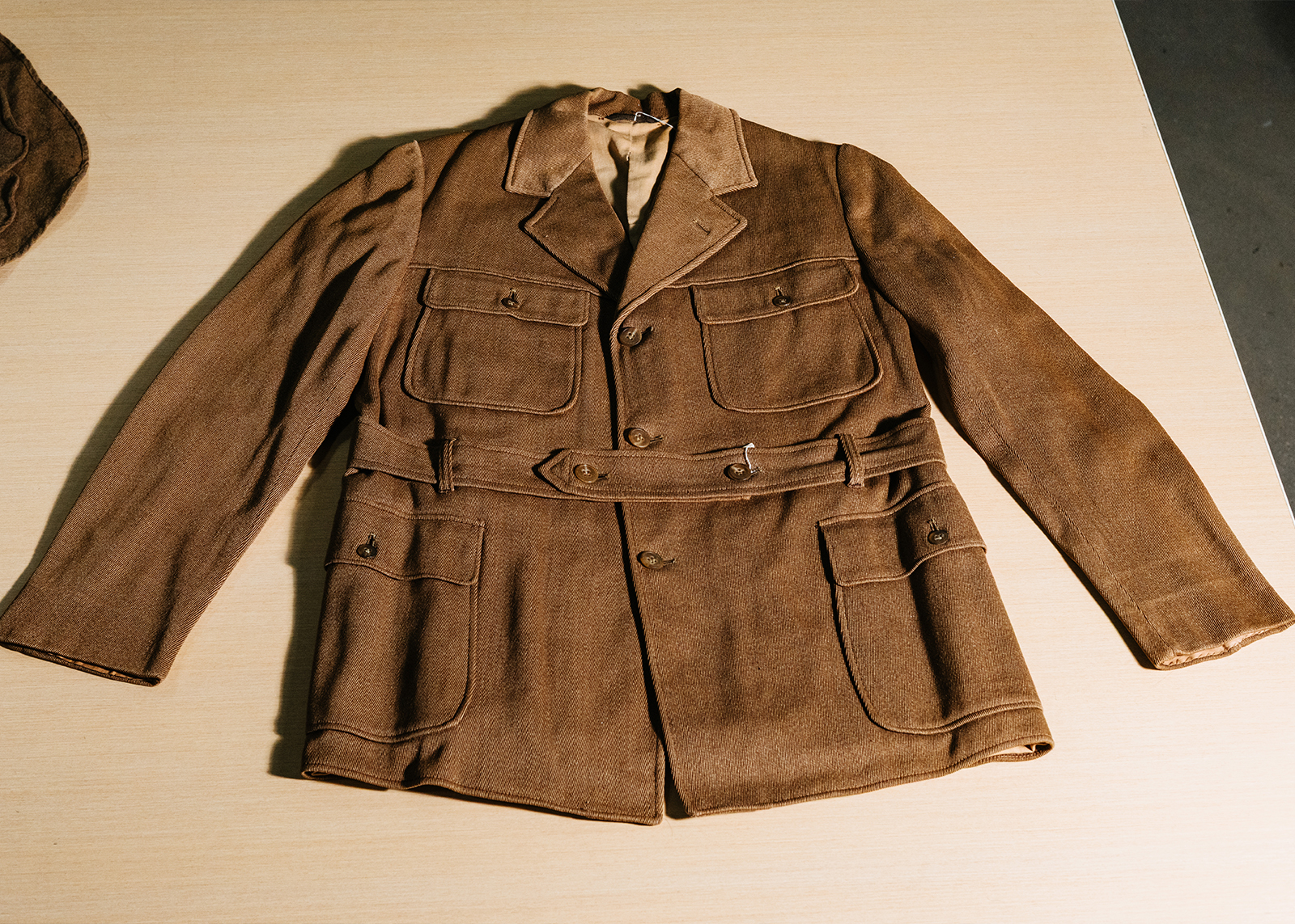 A vintage brown motorcycle jacket with multiple front pockets, belt, and button closure.