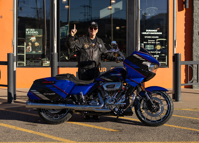 Black & Orange Tier winner Jeff Guynes stands giving a number one hand sign with his new 2025 CVO Road Glide in front of Durango Harley-Davidson