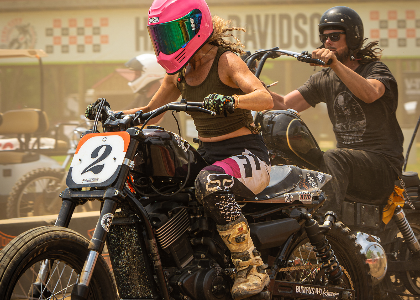 A woman and man on their own bikes in a dirt track race.