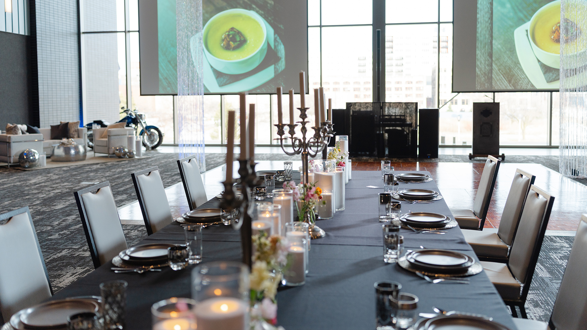 Long dining table with candles, floral decor, and stage display