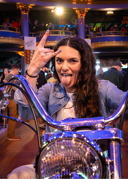 Person sitting on a motorcycle and making a hand gesture during Mama Tried indoor bike show